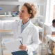 Scientist in a biotechnology lab holding a clipboard and analyzing medical supplies.
