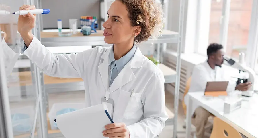 Scientist in a biotechnology lab holding a clipboard and analyzing medical supplies.