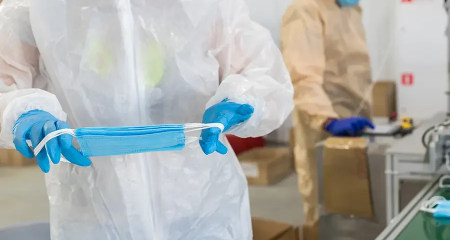 Workers handling the industrial production of protective medical masks in a factory.