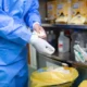 Male surgeon removing surgical gloves in a hospital operating room after a procedure.