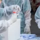 Group of health workers collecting saliva samples for medical testing in a public outdoor area.