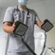 Doctor wearing a medical mask and stethoscope using a defibrillator in a clinical setting.