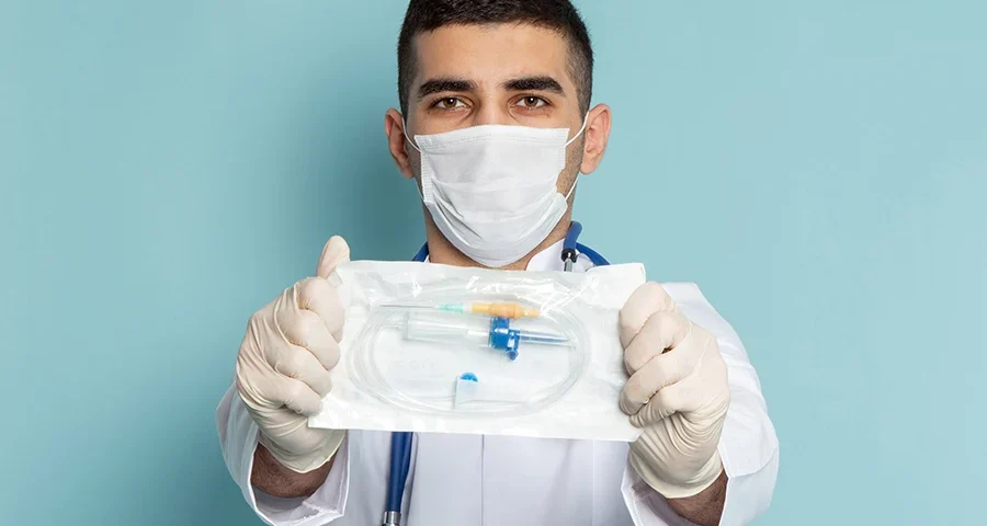 Male doctor in white coat with a blue stethoscope standing confidently.