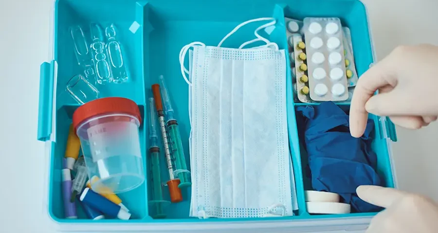 Close-up of a home first aid kit with various medical items inside.