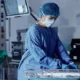 Female doctor preparing surgical equipment in a hospital operating room with proper PPE.