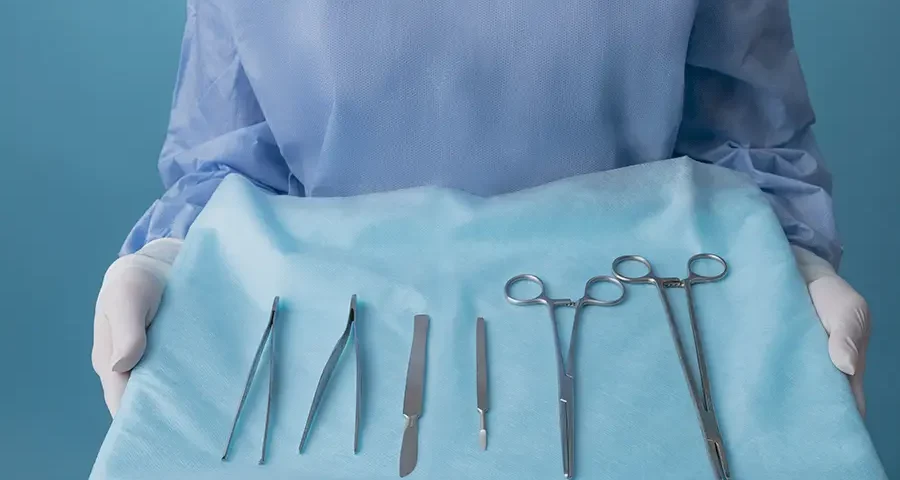 Medical professional holding a tray filled with surgical instruments, ready for use in an operation.