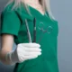 Female doctor holding a scalpel and other surgical instruments while wearing protective gloves.