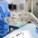 Operating room assistant handing surgical instruments to surgeons during a medical procedure.