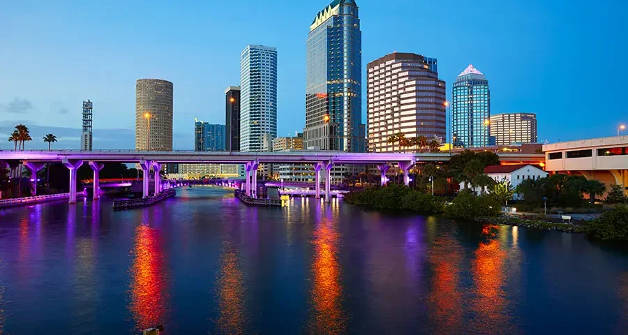 Tampa, Florida skyline lit by sunset with reflections on the water.