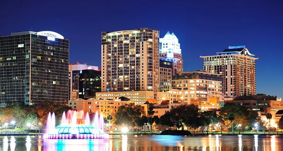Night cityscape of Orlando, Florida, with city lights reflected on the water.