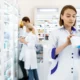 Serious pharmacist closely inspecting a medicine bottle in her hands.