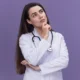 Young female doctor in lab coat with stethoscope, thinking and looking up.