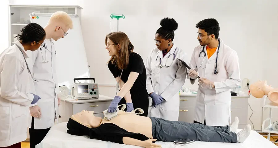Medical students practicing CPR on a training mannequin in class.