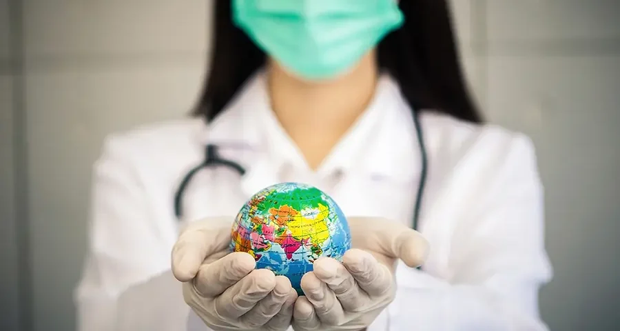 Female doctor holding globe, symbolizing sustainable use of medical resources.