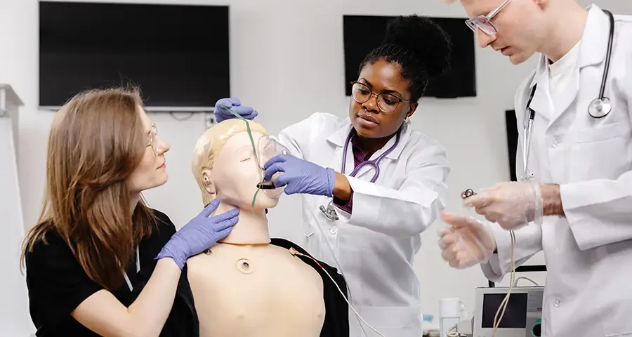 Medical student practicing clinical skills on a training mannequin in a simulation setting.