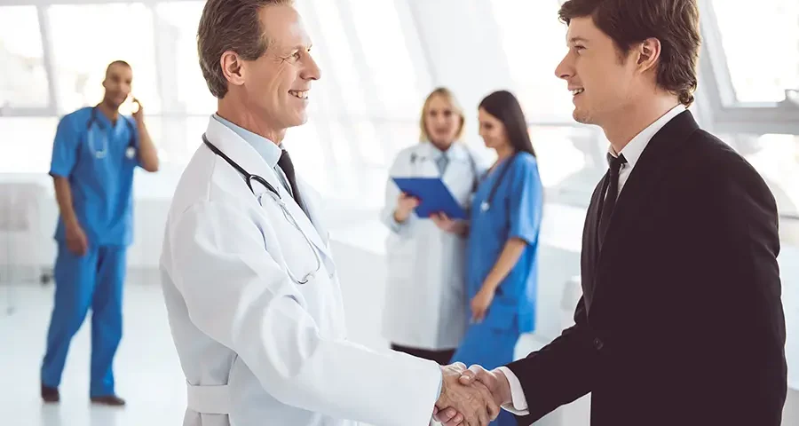 Doctor and business professional shaking hands, symbolizing a reliable medical supply partnership.