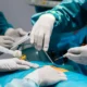Surgeons in full scrubs performing a medical procedure in an operating room, demonstrating clinical training.
