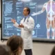 Medical students attending a lecture with digital displays showing human anatomy in a modern classroom setting.