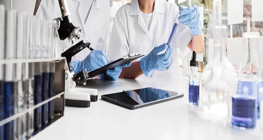 Two female scientists conducting a chemical experiment in a lab, representing collaborative medical research.