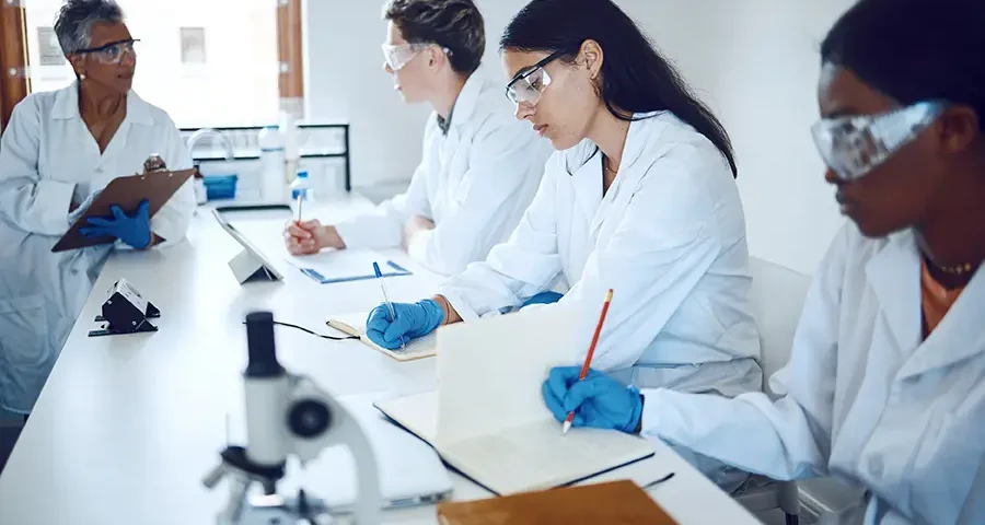 Medical students collaborating with a professor in a laboratory setting for research and training.