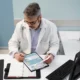 High-angle view of a doctor reviewing documents, illustrating budgeting or cost-saving in healthcare