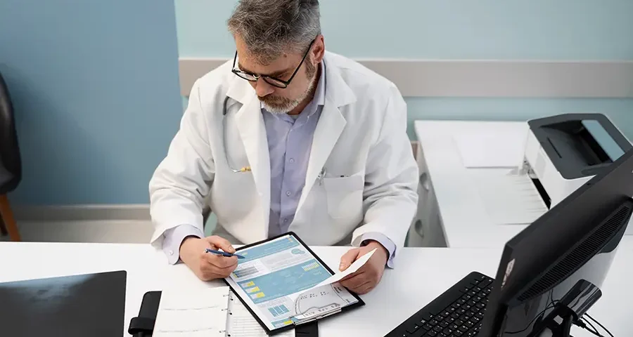High-angle view of a doctor reviewing documents, illustrating budgeting or cost-saving in healthcare